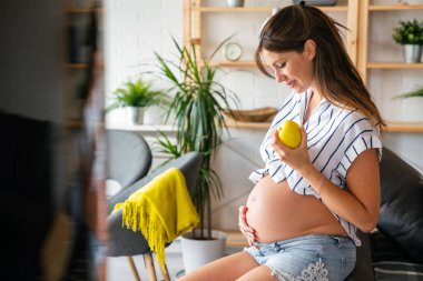 Hamilelik boyunca beslenme ve diyet. Hamile genç bir kadın sağlıklı gıda ve vitaminlere dikkat eder.