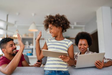 Birlikte tatil yapmayı planlıyoruz. Mutlu Afro-Amerikan babası, annesi ve kızı dijital cihaz kullanıyor, Mutluluk teknolojisi insanlar konsepti.