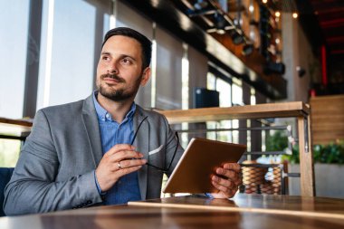 Mutlu halefin portresi genç iş adamı, lider, yönetici dijital tablet kullanarak çalışıyor. İş teknolojisi kavramı.