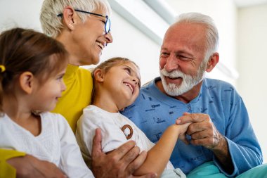 Tıp, destek, aile, sağlık ve insan konsepti. Mutlu torunlar büyükbabasını hastanede ziyaret ediyor.