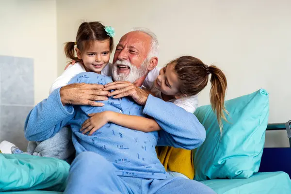 Little girls visiting grandfather in hospital, who is recovering from coronavirus. Healthcare, virus, family support concept