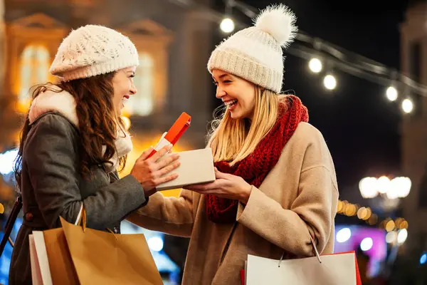 Happy young women friends exchanging christmas present. Happiness people friend shopping xmas concept