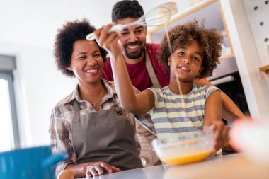 Mutlu Afro-Amerikan gülümseyen ailesi mutfakta sağlıklı yemekler hazırlıyor, hafta sonları birlikte eğleniyorlar.