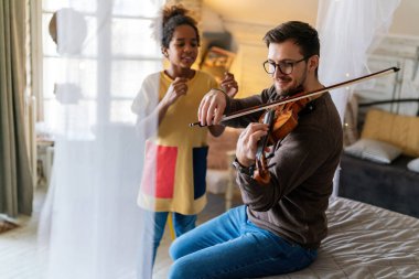 Müzik çok eğlenceli. Genç baba, evlatlık kızına keman çalmayı ve gülümsemeyi öğretiyor. Tek ebeveyn çocuk mutluluğu kavramı.