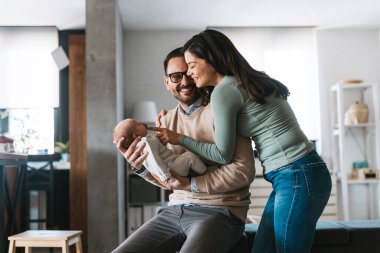 Barışçıl, genç, evli bir çift aile olmanın keyfini çıkarıyor, ebeveynler kucağında yeni doğmuş bir bebek, birbirlerine yakın duruyorlar. Ebeveynlik, doğum, ilişki kavramı