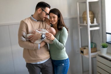 Genç ebeveynlerin ve yeni doğmuş bebeklerin portresi. Baba ve anne yeni doğmuş güzel bir çocuğu öpüp kucaklıyor. Aşk, mutlu babalık ve annelik kavramı..