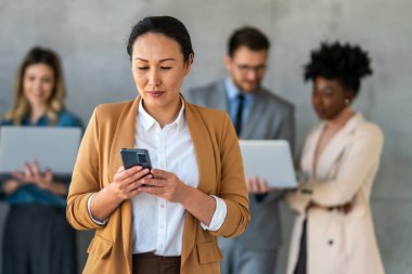 Arka planda çok ırklı meslektaşlar çalışırken başarılı iş kadını ve girişimcinin portresi.