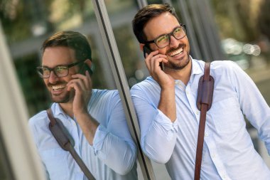 Ofisin önünde akıllı telefon kullanan başarılı bir iş adamı. Teknoloji işi mutluluk kavramı.