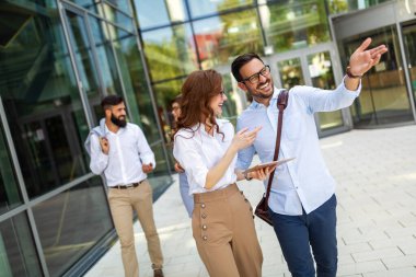 Bir grup iş adamı ofis binalarının önünde yürüyorlar. İş adamları başarı kavramı.