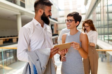 Modern ofisteki iş arkadaşları birlikte çalışıp tablet kullanıyorlar.
