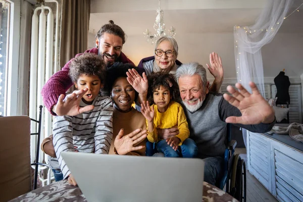 Happy multigeneration diverse family gathering around laptop and having fun during a video call
