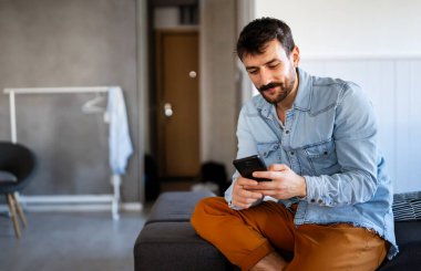 Akıllı telefon teknolojisi insanlarla iletişim konsepti. Genç adam cep telefonunu iş, sosyal medya veya rahatlama için kullanıyor