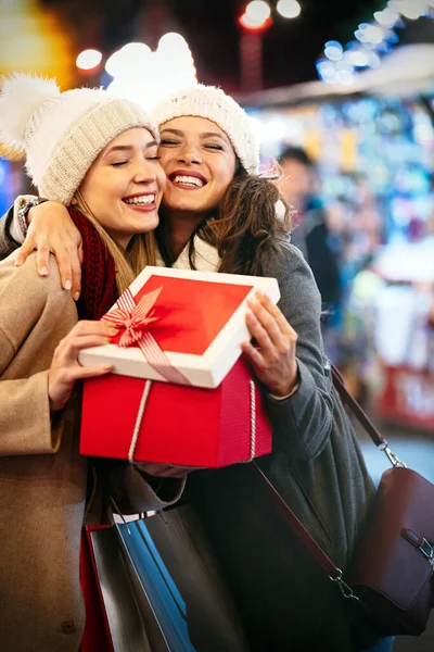 Happy young women friends exchanging christmas present. Happiness people friend shopping xmas concept