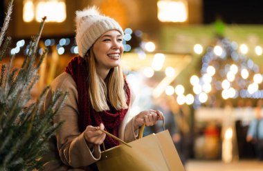 Markette Noel hediyesini ve ağacı seçen mutlu, genç bir kadın. Tatil mutluluğu insanlar konsepti