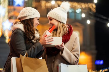 Mutlu kadın arkadaşlar Noel için hediyelerini değiştiriyorlar. Alışveriş xmas mutluluk satış insanları konsepti