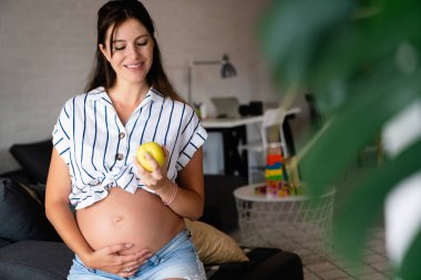 Hamilelik boyunca beslenme ve diyet. Hamile genç bir kadın sağlıklı gıda ve vitaminlere dikkat eder.