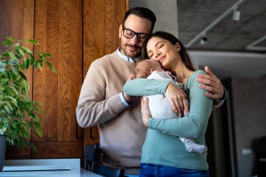 Mutlu bir genç adam ve kadın holding yeni doğan şirin bebek portre beyaz unisex kılığına girmiş. Beyaz gülümseyen baba ve anne kucaklayan şefkatle çok güzel yeni doğan çocuk. Mutlu aile kavramı