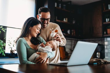 Genç ebeveynlerin ve yeni doğmuş bebeklerin portresi. Baba ve anne yeni doğmuş güzel bir çocuğu öpüp kucaklıyor. Aşk, mutlu babalık ve annelik kavramı..
