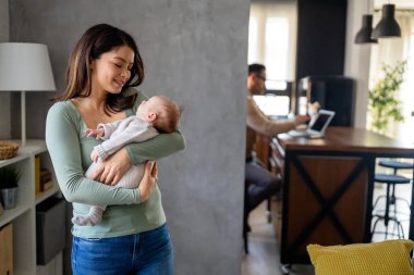 Sevgi dolu bir anne, yeni doğmuş bebeğini evde taşıyor. Mutlu bir annenin parlak portresi. Elinde uyuyan bir bebeği tutuyor..