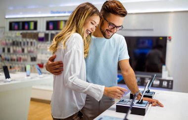 Teknoloji alışverişi dijital cihaz konsepti. Mobil dükkanından yeni bir akıllı telefon alan mutlu gençler.