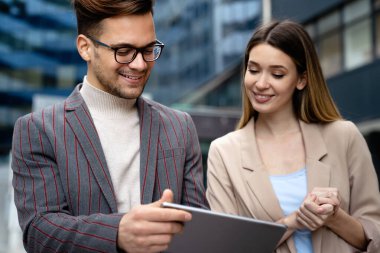 Başarılı iş arkadaşları dijital cihazlar üzerinde birlikte çalışıyorlar. İş adamları şehir konsepti üzerinde çalışıyor