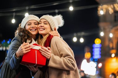 Mutlu genç bayan arkadaşlar Noel hediyelerini değiş tokuş ediyorlar. Mutluluk insanlar arkadaş alışveriş xmas konsepti