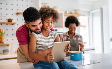 Mutlu Afro-Amerikan ailesi evde aletle eğleniyor. Siyah ebeveynler ve çocuklar dijital tablet kullanıyorlar
