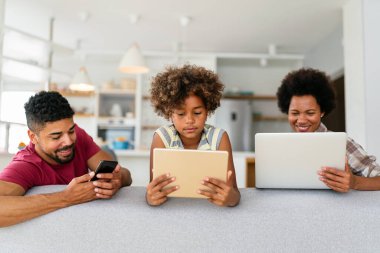 Teknolojik cihazlara takıntılı mutlu Afro-Amerikan genç ailesi dijital tablet, bilgisayar, akıllı telefonlar kullanıyor..
