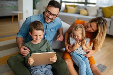 Mutlu genç aile evde eğleniyor. Çocuklu aileler tablet kullanıyor. İnsanlar mutluluk kavramını sever.