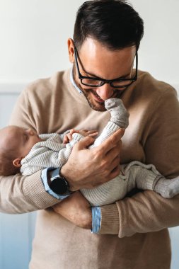 Yeni doğmuş bebeğini kucaklayan ve öpen bir babanın portresi. Erkek ebeveyn çocuğunu tutuyor. Otantik yaşam tarzı dokunaklı bir an. Bekar baba aile hayatı konsepti.