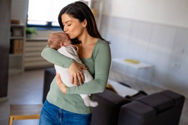 Sevgi dolu bir anne, yeni doğmuş bebeğini evde taşıyor. Mutlu bir annenin parlak portresi. Elinde uyuyan bir bebeği tutuyor..