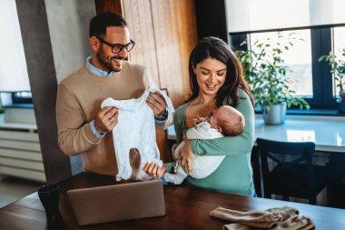 Genç ebeveynlerin ve yeni doğmuş bebeklerin portresi. Baba ve anne yeni doğmuş güzel bir çocuğu öpüp kucaklıyor. Aşk, mutlu babalık ve annelik kavramı..