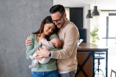 Barışçıl, genç, evli bir çift aile olmanın keyfini çıkarıyor, ebeveynler kucağında yeni doğmuş bir bebek, birbirlerine yakın duruyorlar. Ebeveynlik, doğum, ilişki kavramı