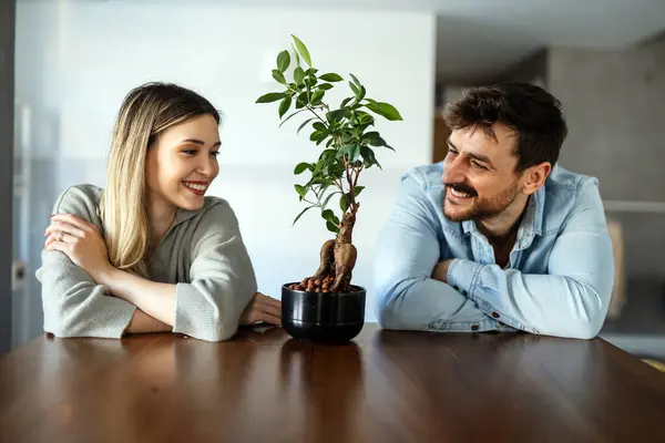 Plant care. Nature protection concept. Smiling environmentally friendly couple with houseplant.