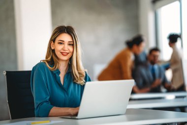 Genç ve başarılı iş kadını şirket ofisinde dizüstü bilgisayarla çalışıyor. Teknoloji insanları kavramı