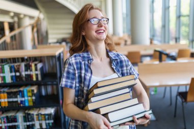 Eğitim kütüphanesi, üniversite eğitimi ve insanların konsepti. Üniversite kütüphanesinde kitap okuyan gülümseyen öğrenci kız.