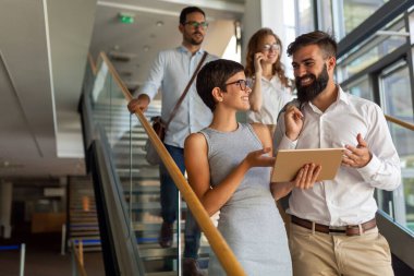 Bir grup iş adamı ofis pencerelerinin önünde dijital tablet kullanıyorlar. Takım çalışması, iş buluşması konsepti.