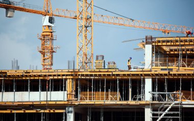 Large modern construction site including several cranes working on a building complex clipart