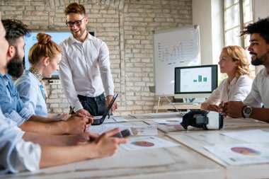 Bir grup çok ırklı iş adamı ofis masasında mali raporları analiz ediyor ve ofiste bir takım olarak çalışıyorlar.