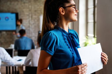 Takım toplantısında gülümseyen başarılı kadın iş adamı. Yönetim kurulunda iş arkadaşlarıyla birlikte kendine güvenen bir iş kadınının portresi. Belge tutulurken poz