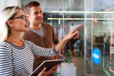 İş çözümleri, teknoloji, başarı ve strateji kavramı. İş arkadaşları ofiste çalışıyor ve beyin fırtınası yapıyorlar.