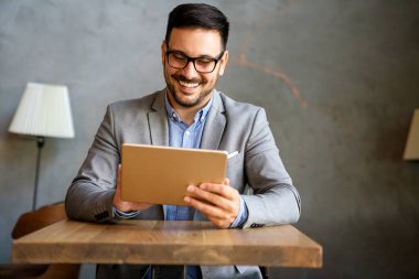 Mutlu halefin portresi genç iş adamı, lider, yönetici dijital tablet kullanarak çalışıyor. İş teknolojisi kavramı.