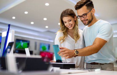 Teknoloji alışverişi dijital cihaz konsepti. Mobil dükkanından yeni bir akıllı telefon alan mutlu gençler.