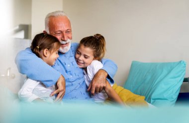 Mutlu kıdemli adam Coronavirus 'tan kurtuluyor. Torunları onu ziyaret ediyor.