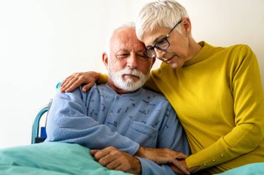 Tıp, destek, sağlık ve insan konsepti. Yaşlı kadın hasta kocasını hastanede ziyaret ediyor.