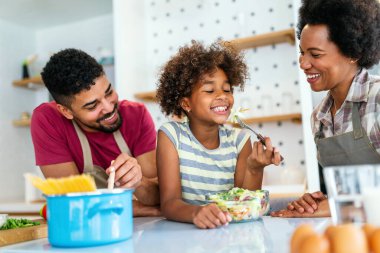 Mutlu Afro-Amerikan ailesi mutfakta eğleniyor ve birlikte yemek pişiriyor. Evde sağlıklı yiyecekler..