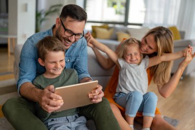 Mutlu genç aile evde eğleniyor. Çocuklu aileler tablet kullanıyor. İnsanlar mutluluk kavramını sever.