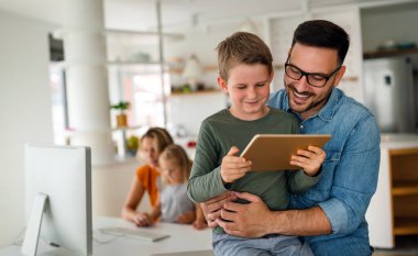 E- öğrenim için dijital tablet kullanan baba ve çocuğun portresi. Eğitimde evde eğitim veren dijital cihaz çocuk kavramı.