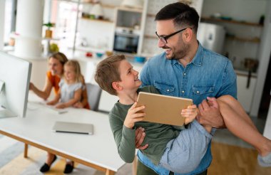 Uzaktan öğrenme, online eğitim, ev işi okulu konsepti. Evde dijital cihazları olan mutlu bir aile.