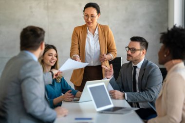 Çok ırklı başarılı iş adamları, analitik rapor sunan profesyoneller modern ofisteki meslektaşlarıyla birlikte çalışıyorlar.